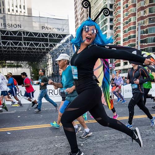 A Bay to Breakers attendee in a blue wig and a fabulous butterfly costume runs gleefully